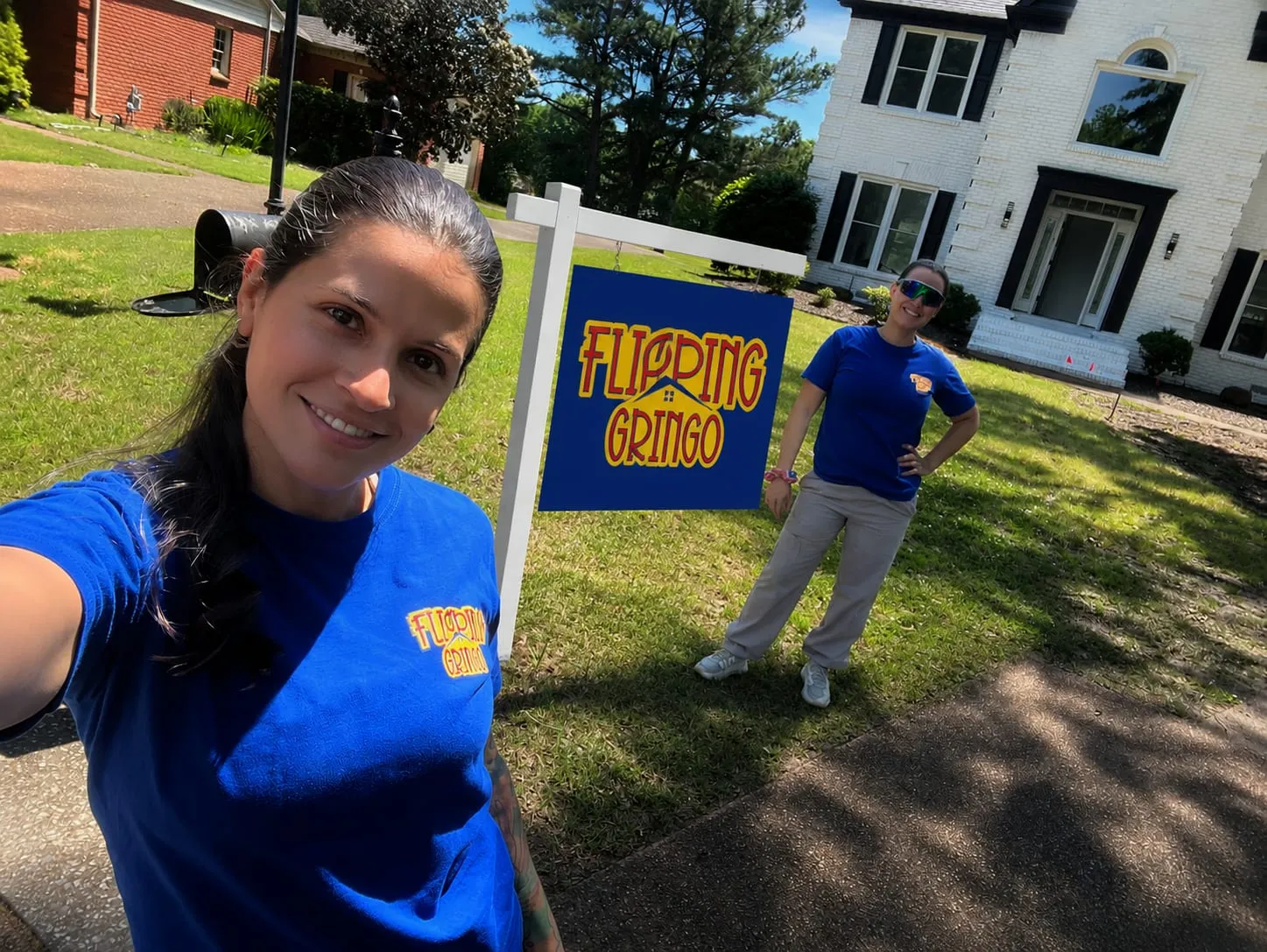 The Flipping Gringo team beside a branded yard sign at a finished home