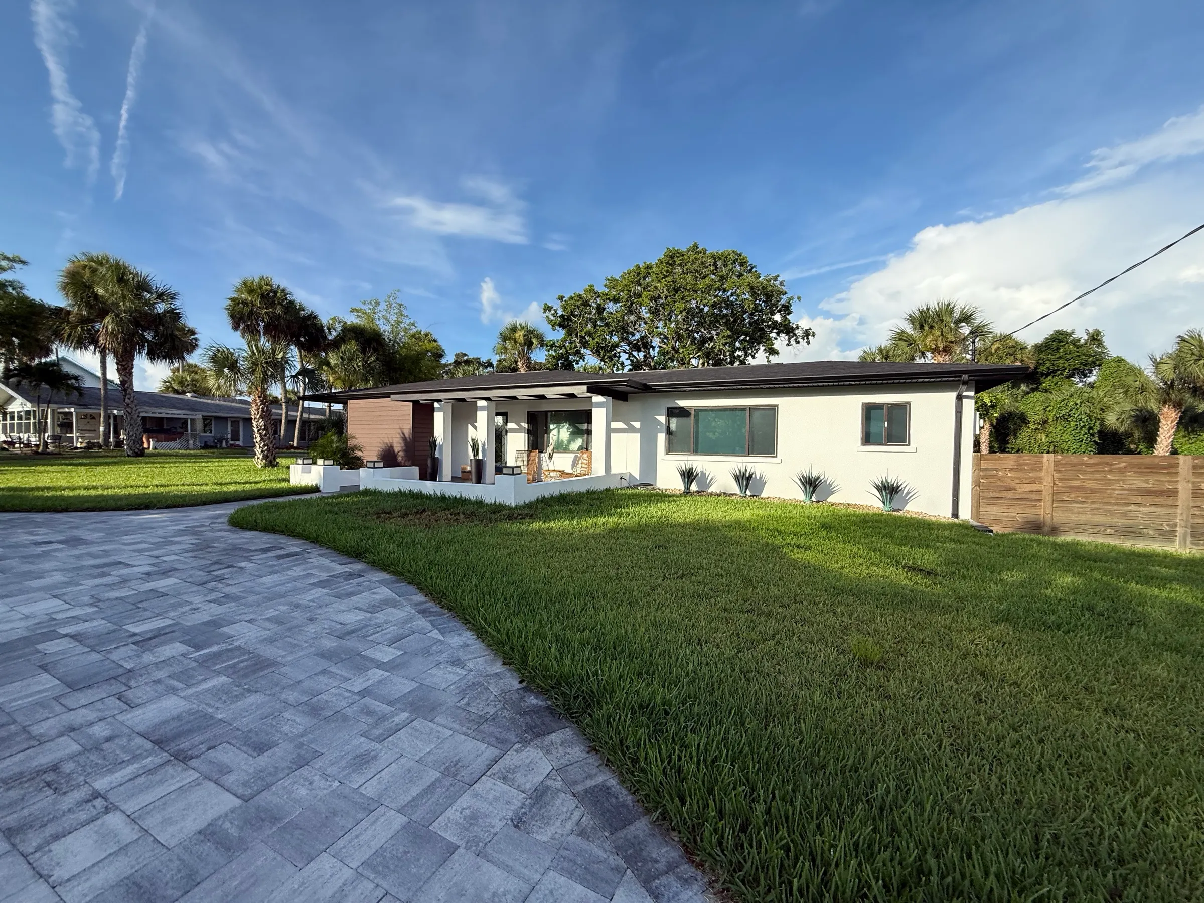 A bright, fully renovated single-story home with fresh landscaping and a paver driveway